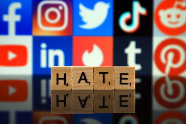 Schriftzug Hate vor Logos von sozialen Netzwerken