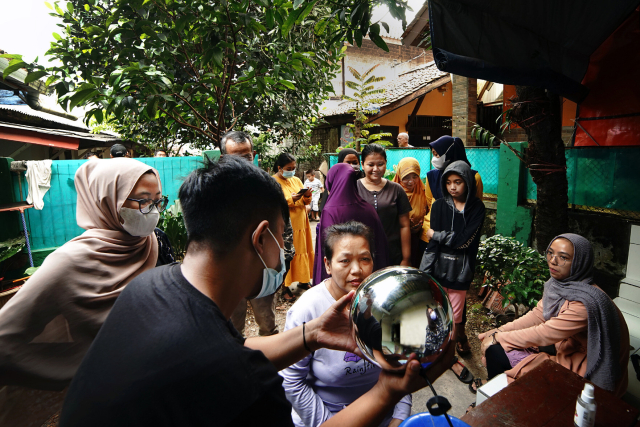 Frau in Indonesien, die ihre Iris mit einem Silberball scannen lässt.