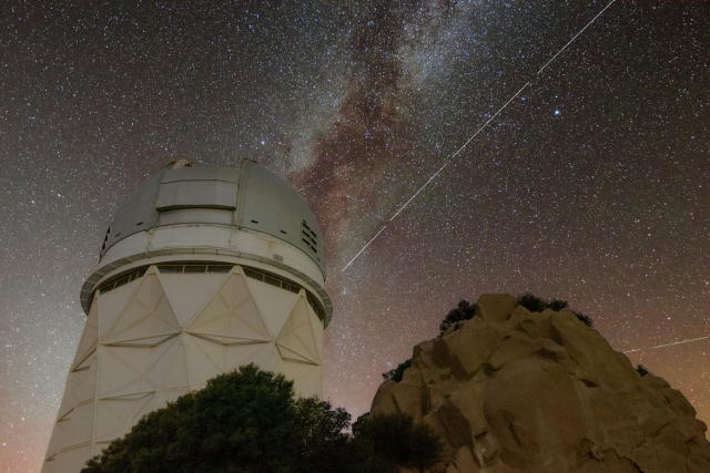 Spur von BlueWalker 3 am Sternenhimmel über einem Teleskop
