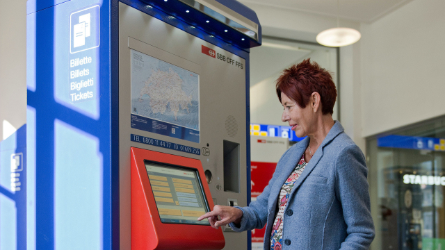 Eine Frau an einem Ticketautomaten der Schweizer Bahn