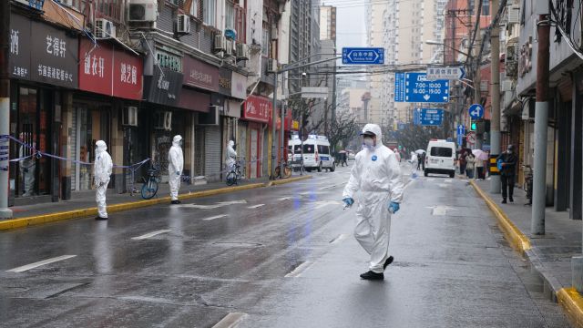 Personen in Schutzanzügen auf Straße in China