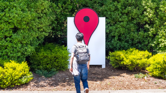 Mann läuft vor Statue von Googles Standort-Pin