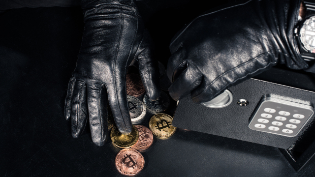 Hände in Handschuhen an Tresor mit Bitcoins