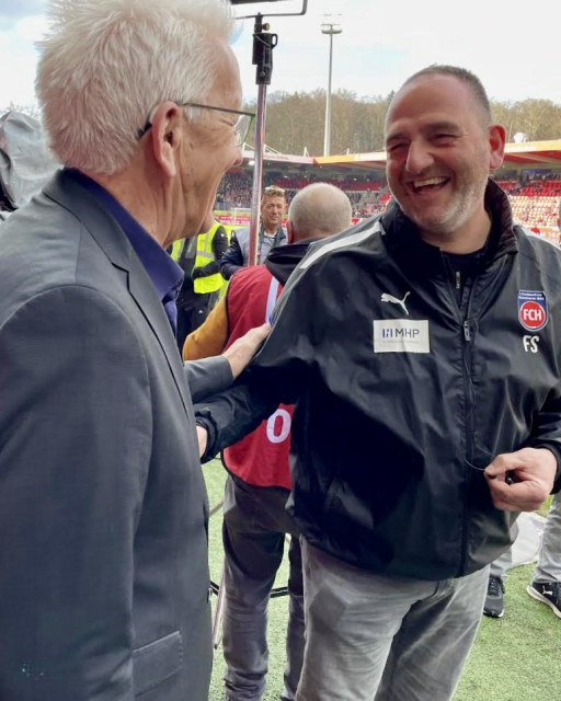 Ministerpräsident (links) lacht mit Cheftrainer des 1. FC Heidenheim, Frank Schmidt (rechts).