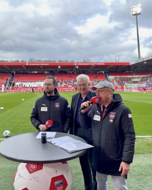 Ministerpräsident Kretschmann (mitte) zwischen dem stv. Pressesprecher des 1. FC Heidenheim, Tim Janssen (links) und Stadionsprecher Peter Barth (rechts).