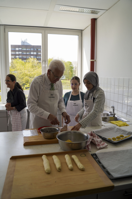 Ministerpräsident Kretschmann besucht den Unterricht im Berufsschulzentrum Leonberg und hilft, Gebäck vorzubereiten.