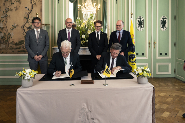 Ministerpräsident Kretschmann (links, vorne) und Ministerpräsident Jambon von Flandern (rechts vorne) unterzeichnen eine Absichtserklärtung. Bezeugt werden die Unterschriften von Staatsminister Dr. Florian Stegmann (hintere Reihe, 2. von rechts) und Kabinettschef des Ministerpräsidenten Jambon, Jeroen Overmeer (hintere Reihe, 2. links). Copyright: Government of Flanders