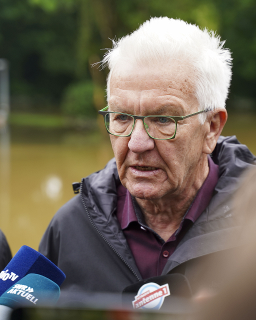 Porträt von Ministerpräsident Winfried Kretschmann vor dem überfluteten Schulhof in Kehlen in Meckenbeuren.