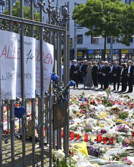 Blumen und Kerzen liegen bei einer Gedenkminute auf dem Marktplatz in Mannheim zum Gedenken an einen getöteten Polizisten. Im Hintergrund Winfried Kretschmann (Bündnis 90/Die Grünen), Ministerpräsident von Baden-Württemberg (v.l.) Angehörige des getöteten Polizisten, Thomas Strobl (CDU), Innenminister von Baden-Württemberg und Bundespräsident Frank-Walter Steinmeier. Eine Woche zuvor wurde auf dem Platz ein Polizist bei einem Messerangriff getötet. Bildquelle: © picture alliance/dpa | Bernd Weißbrod