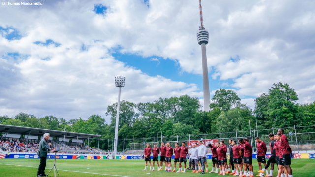 Ministerpräsident Kretschmann hält eine Rede vor der Schweizer Nationalmannschaft. Er steht vor ihnen auf dem Rasen des Fußballstadions. Foto: Thomas Niedermüller