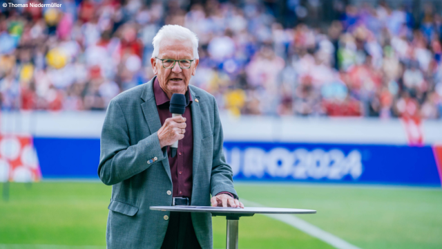 Ministerpräsident Kretschmann steht mit einem Mikrofon im Fußballstadion. Foto: Thomas Niedermüller
