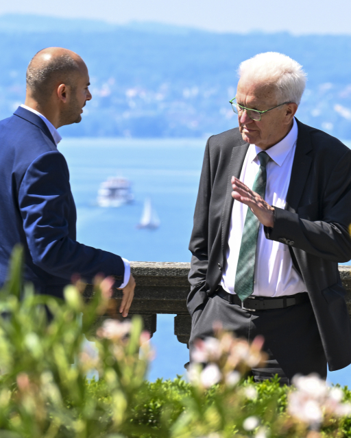 Danyal Bayaz, Finanzminister von Baden-Württemberg und Winfried Kretschmann, Ministerpräsident von Baden-Württemberg, stehen vor dem Bodensee am 25.06.2024.