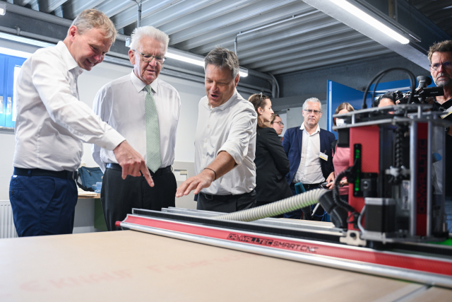 Hermann Blattner (l-r), Geschäftsführer des Handwerksbetriebs Christian Gröber GmbH & Co. KG, Winfried Kretschmann (Grüne), Ministerpräsident von Baden-Württemberg, und Robert Habeck (Bündnis 90/Die Grünen), Bundesminister für Wirtschaft und Klimaschutz, unterhalten sich beim Besuch des Handwerksbetriebs im Rahmen einer mehrtägigen Sommerreise des Bundeswirtschaftsminister an einer Fräse für Flächenheizungen. Die Firma hat sich insbesondere auf die energetische Sanierung von Altbauten spezialisiert.