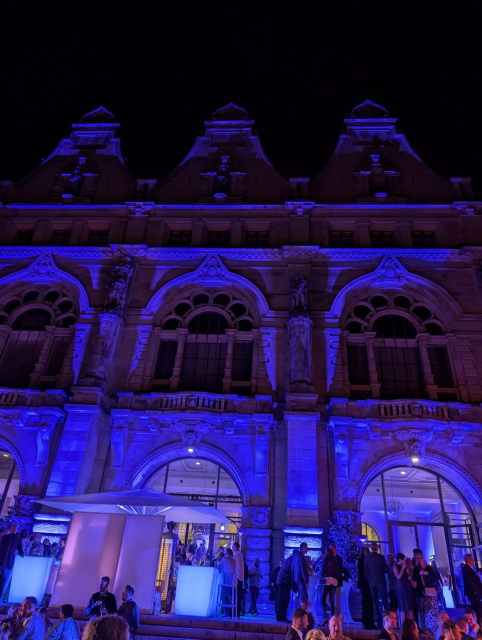 Blau angestrahltes Rathaus mit Menschen im Vordergrund