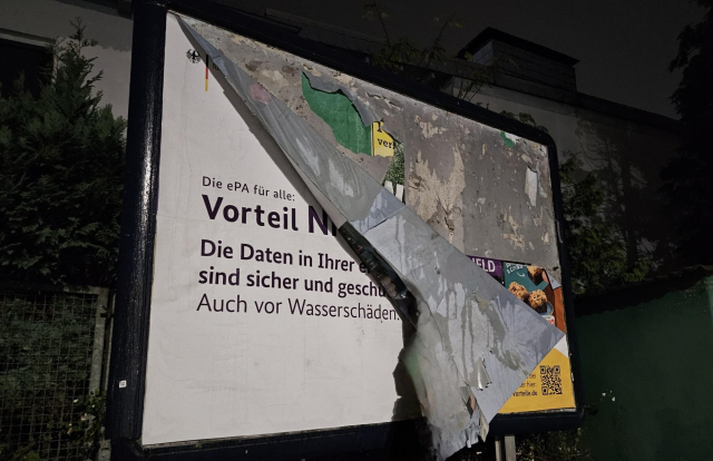 Vorteil der elektronischen Patientenakte auf einem Werbeplakat. Auf dem Plakat heißt es, dass die Daten auch vor Wasserschäden geschützt sind. Das Plakat ist durchnässt vom Regen.