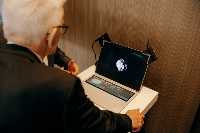 Ministerpräsident Kretschmann beugt sich über ein aufgeklapptes Laptop. Man sieht ihn von hinten. Auf dem Bildschirm des Laptops ist ein Ultraschall-Bild zu sehen.