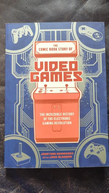 Frontcover von The Comic Book Story of Videogames
The incredible history of the electronic gaming revolution

Im Hintergrund ein Gaming Cabinet, in den Ecken diverse Controller und ein Joystick