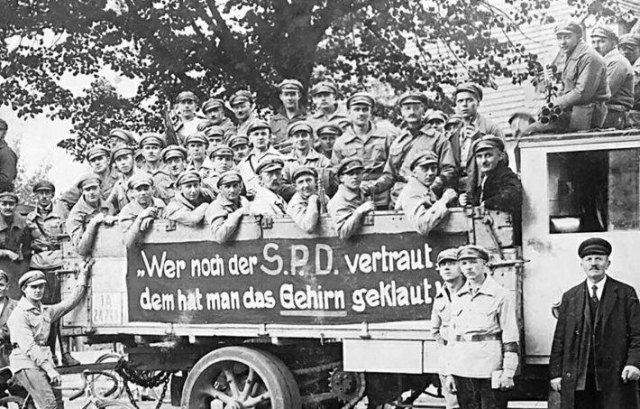 Schwarz Weiss Bild von Arbeitern auf einem Wagen mit dem Banner: "Wer nich der SPD vertraut dem hat man das Gehirn geklaut"